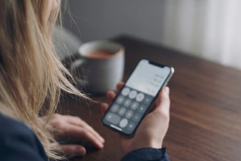 Kvinna som använder kalkylator på sin mobil